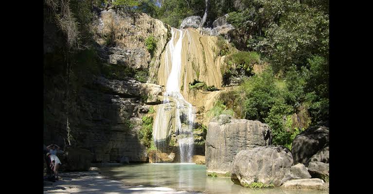 A waterfall cascading over limestone into a quiet pool in the Tsiribihina river gorge